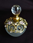 Perfumeiro em vidro satinado com acabamentos em metal cinzelado ricamente ornado com pedras lapidadas e com tampa lapidada ao estilo diamante. Medida 8,5cm de altura.