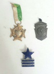 Duas medalhas e uma insígnia,  uma medalha escolar ao mérito, uma medalha de torneio da marinha e uma insígnia do colégio militar.