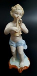 Escultura em biscuit representando querubim com instrumento, med. 16 centímetros.
