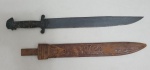 Antiga espada facão africano com lâmina em aço carbono,  cabo em madeira decorado com aplique em metal no formato de cabeça, e bainha em couro med. 42 centímetros.