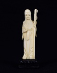 Arte Oriental -Escultura de marfim representando sábio segurando fruto e cajado. Base de madeira. Marcas do tempo. Desgastes. Med. 9 x 3,5  x 2 cm (medidas totais); 8 x 2 x 1 cm (escultura). Acervo Particular São Paulo/SP