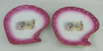 Par de covilhetes na forma de conchas em porcelana, decoradas em reserva retratando Lordes em reunião. Borda com flores esmaltada. Podem ser usados para decoração de parede. Med. 23x31 cm.
