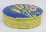 Porta joias ovalado em faiança tcheca, policromada, decorada na tampa com pintura de flores e espigas de trigo em relevo. Med. 9x22x13 cm.