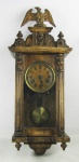 Relógio de parede, marca da manufatura Junghans, com caixa em madeira entalhada e encimado com figura de pássaro. Funcionando, só necessitando regulagem. Med. 65x27x 16 cm.