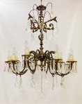 Antigo lustre estilo Versalles, para 10 luzes, em bronze trabalhado com folhagens e volutas. Dez braços recurvos com contas e pingentes em cristal, com lapidações facetadas. Alt. 94 cm.
