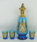 Conjunto de licoreiro e 3 copinhos em vidro veneziano, na cor azul, decorados com pintura floral e ricos trabalhos em dourado. Alt. licoreiro 24 cm.