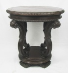 Mesa de apoio em madeira entalhada. Tampo circular com borda trabalhada em gomos, sustentado por 4 pernas recurvas com entalhes em volutas, sobre base circular. Marcas de uso. Med. 65,5x65,5 cm.