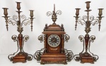 Belo e raro terno francês, do séc. XIX, estilo medieval, composto de relógio e par de candelabros para 3 velas, em madeira e bronze. Relógio da manufatura Pêndulo Paris. Mostrador esmaltado contendo placa com os dizeres. C.H. GAUTIER - Paris - Bordeaux. Alt. do relógio 58 cm. Alt. do candelabro 57 cm.