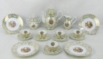 A) Serviço para café em porcelana Real, com decoração floral em dourado e em reserva cena com ninfas em policromia, composto de bule, leiteira, açucareiro e 5 xícaras. Alt. bule 18 cm. B) Quatro pratos para sobremesa em porcelana Mauá, com decoração floral em dourado e figuras orientais em policromia. Diam. 15 cm.