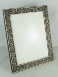 Porta retratos em madeira e prata portuguesa contrastada, com marca do prateiro Reis Porto filhos Ltda. Decorado com trabalhos de volutas, folhagens e detalhes vazados. Apresenta quebra na haste do suporte na parte de trás. Med. 33x27 cm.