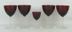 Cinco taças em vidro no tom vermelho com hastes e bases translúcidas, sendo 4 para vinho branco e uma para licor. Alts. 13,5 e 9,5cm.
