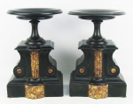 Par de colunas baixas em mármore negro, decorados com detalhes em mármore rajado. Tampos com um pequeno lascado na borda de cada, e bases com bicados. Alts. 27cm. Diamts. tampos 18,5cm.