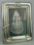 Porta retratos em madeira e prata contrastado, decorado com trabalhos de gomos e sulcos em relevo. Prata com pequenas mossas. Med. 19x15cm.