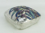 Antiga caixa em metal prateado, decorada com folhagens policromadas e esmaltadas em relevo sobre a tampa. Apresenta marca / assinatura na base. Pequenos desgastes causados pelo tempo . Med. 7x13,5x13,5cm.
