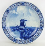 Medalhão em porcelana holandesa, com marca da manufatura Delft no verso, decorado com paisagem com moinhos de vento em tons de azul. DIam. 40,5cm.