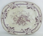 Antiga travessa de coleção, em porcelana européia, decorada com flores e folhagens em tons de vinho. Apresenta manchas causadas pelo tempo. Med. 43x35cm.
