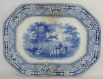 Antiga travessa de coleção em porcelana inglesa com marca da manufatura Woodland W. Baker & Co no verso, decorada com paisagem campestre no tom azul. Med. 43x32,5cm.