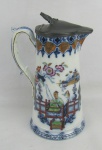 Tankard em porcelana européia com decoração azul borrão e cenas do cotidiano em policromia. Tampa em pewter. Alt. 23,5cm.