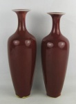 Dois vasos em porcelana sangue de boi, com parte superior bojuda afinando para baixo. Um apresenta restauro. Alts. 30 e 29cm.