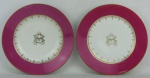 Dois pratos monogramados em porcelana francesa possivelmente da manufatura Limoges, sendo um fundo e um raso. Aba no tom rosa. Detalhes em dourado. Diamts. 24cm.