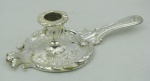 Palmatoria em metal espessurado a prata, com trabalhos de gomos, flores, folhagens e volutas em relevo. Apresenta numeração e resquícios da marca da manufatura na base, podendo ser da manufatura Christofle. Med. 5,5x23x10cm.