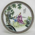 Raro prato de coleção em porcelana chinesa, com marca da manufatura no verso, decorado com pintura de cena de jardim em policromia com detalhes esmaltados e inscrições. Diam. 18,5cm.