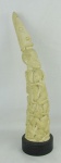 Ponta de presa em marfim africano, ricamente esculpida, formando totem com figuras humanas. Base em madeira. Alt. total 37,5cm.