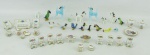 a) Dezessete esculturas miniaturas representando animais, de diversos tamanhos, cores e procedências. Alt. maior e menor 5,5 e 1,5cm. b) Vinte e duas peças miniatura em porcelana de diversos modelos, decorações e procedências, sendo sofá, 2 poltronas, 8 cadeiras, 4 mesas de centro, prato, bule, leiteira, açucareiro, garrafa e 2 xícaras. Alt. maior e menor 3,5 e 1,5cm.
