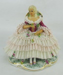 Estatueta de coleção em porcelana policromada, com marca da manufatura Renner na base, representando "A leitura". Detalhes em dourado. Pequenas perdas nas rendas do vestido. Alt. 15,5cm.