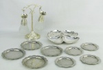 a) Duas peças, sendo petisqueira com marca da manufatura Meridonal, com trabalhos vazados na borda e galheteiro italiano em metal prateado e vidro com trabalhos bico de jaca. Suporte na forma de tronco com galhos que sustenta os recipientes. Alt. galheteiro 21cm. b) Quinze peças em metal prateado com marca da manufatura Regia 90, com trabalhos de folhas e volutas, sendo 11 porta copos e 4 porta garrafas. Pequenas marcas de uso. Diamts. 10 e 12cm.