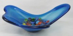 a) Centro de mesa em murano no tom azul. Borda decorada com ondulações. Minúscula batidinha na borda. Med. 13,5x34,5x22,5cm. b) Doze peças decorativas em murano policromado, representando "balas". Três com quebras. Comp. maior e menor 6 e 4,5cm.