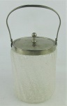 Biscoiteira em vidro jateado trabalhado com gomos em relevo. Guarnições em metal espessurado a prata. Alt. com alça levantada 23,5cm.