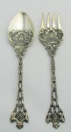 Colher e garfo em metal espessurado a prata, decorados com trabalhos de folhagens e volutas em relevo. Detalhes vazados. Comp. 17,5cm.