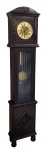 Relógio coluna com caixa em madeira entalhada. Mostrador em metal com números romanos. Portas com vidro. Maquina necessita reparo. Med. 189x40x19,5cm.
