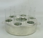 Conjunto com porta caviar e 6 copos para vodka em vidro translúcido, acondicionados a uma base em metal espessurado a prata, com marca da manufatura Soppil Wolff. Med. 13x24,5x20cm.