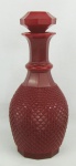 Belo licoreiro em vidro na tonalidade doublet vermelho, decorado com bico de jaca em relevo e facetados. Tampa oitavada. Alt. 29cm.