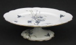 Prato para bolo de pé alto, em porcelana francesa, possivelmente Limoges. Decorado com pintura de pássaros, flores, folhas e borboletas. Detalhes em dourado. Med. 7x22cm.