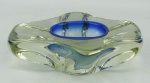 Cinzeiro em murano no tom azul e fumê. Borda trabalhada com largos gomos. Med. 5,5x18x12,5cm.