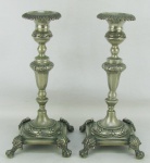 Par de castiçais em metal espessurado a prata, decorados com trabalhos de flores e folhas em relevo. Pés em garra. Um apresenta pequena fissura na haste. Alt. 25cm.