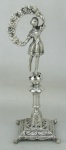 Paliteiro em metal espessurado a prata, encimado por figura feminina em alto relevo. Parte central com pequenas mossas. Alt. 17,5cm.