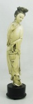 Escultura monobloco em marfim oriental representando "Dama no jardim". Base em madeira. Falta adereço em uma das mãos. Alt. total 34,5cm.