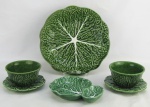 Quatro peças em faiança portuguesa, tendo uma resquícios da manufatura Bordalo Pinheiro no verso, com decoração esmaltada de folhagens no tom verde, sendo prato para bolo, petisqueira e 2 bowls com presentoir. Diam. prato 30,5cm.