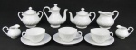 Nove peças em porcelana portuguesa, com marca da manufatura Vista Alegre, decoradas com gomos curvos em relevo, sendo 2 bules, açucareiro, leiteira, 2 leiteiras individuais e 3 xícaras para chá. Alt. bule maior 13,5cm.