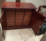 Cômoda em madeira entalhada. Tampo retangular sobre duas bandas de portas, contendo em seu interior 24 gavetinhas. Med. 94x110x53cm.  ATENCÃO: O bem será apregoado por foto e devera ser retirado mediante agendamento, na residência do proprietário, em Ipanema/RJ, sendo de exclusiva responsabilidade do arrematante. Será desfeita a arrematação, sem quaisquer outras consequências, caso não possa ser retirado o bem pelo elevador ou escada da residência.