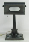 Luminária de mesa / tinteiro em metal patinado. Cúpula com vidro foscado. Base com dois recipientes para tinta em vidro. Metal com 4 pequenos desgastes causados pelo tempo. Alt. 46cm.