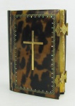 Antigo missal com capa em casco de tartaruga, decorado com uma cruz em metal dourado, e detalhes em madreperola. Junção da lateral com a capa apresenta colagem. Med. 12x9x3cm.