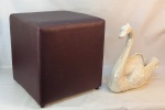 a) Floreira em faiança leitosa, com brilho iridiscente, representando "cisne". Apresenta batidinhas com perdas no esmalte. Med. 40x44x20,5cm.b)  Puff Tok & Stok estofado e forrado no tom vinho. Pequenas marcas de uso. Med. 42,5x41x41cm.