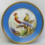 Prato de coleção em porcelana francesa, com marca da manufatura Limoges. Aba no tom azul, e ao centro pintura assinada de paisagem com pássaros. Detalhes em dourado. DIam. 24,5cm.