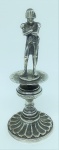 Paliteiro em metal espessurado a prata, na forma de Napoleão. Base circular com trabalhos em sulcos. Alt. 14 cm.