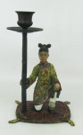 Castiçal em petit bronze oriental, policromado, adornado por menina em alto relevo. Alt. 19,5cm.